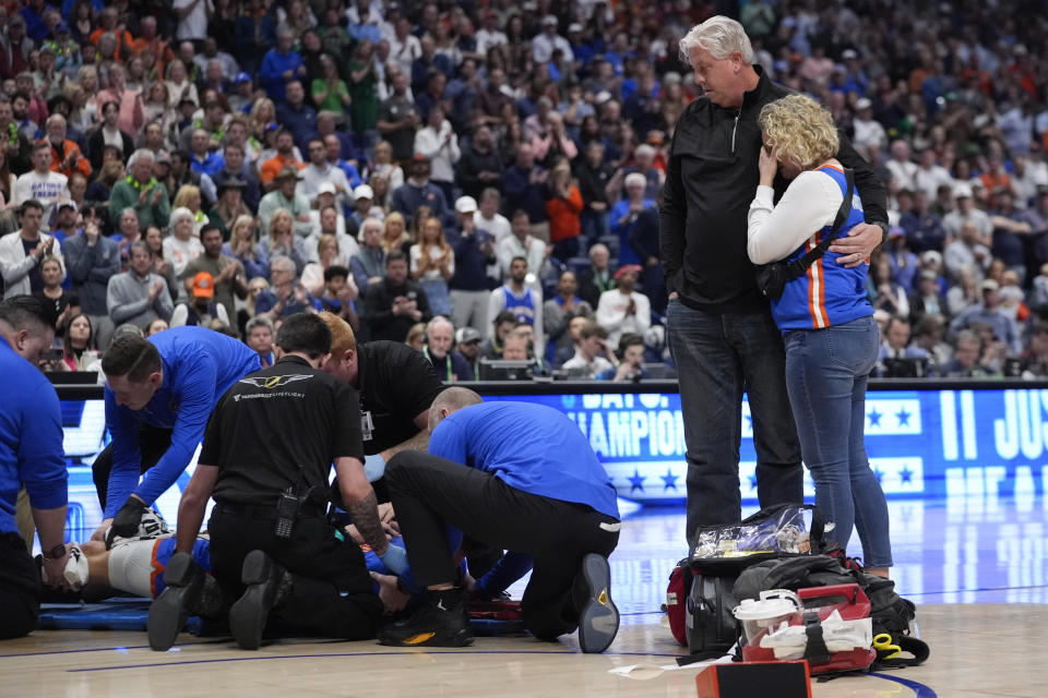 Danielle and Benjamin Handlogten look on as medical personnel tend to their son Florida center Micah Handlogten after he injured his leg during the first half of an NCAA college basketball game against Auburn at the Southeastern Conference tournament, Sunday, March 17, 2024, in Nashville, Tenn. Handlogten was taken off the court on a stretcher. (AP Photo/John Bazemore)
