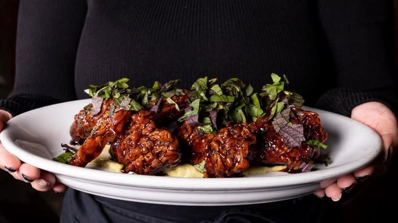 server holding plate of fried chicken