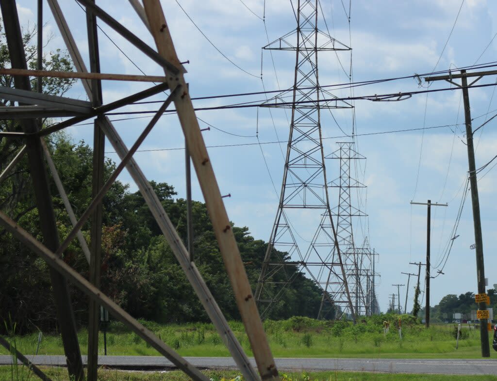 A row of energy transmission towers carries electricity along a highway outside of LaPlace