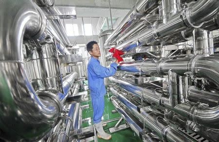 An employee wipes equipment on the production line of hawthorn red wine at a factory in Weifang, Shandong province July 28, 2013. REUTERS/China Daily