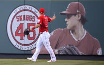 FILE - Los Angeles Angels center fielder Mike Trout gestures toward a photo of Tyler Skaggs in center field prior to a baseball game against the Detroit Tigers in Anaheim, Calif., July 29, 2019. A former Angels employee was convicted Thursday, Feb. 17, 2022, of providing Angels pitcher Skaggs the drugs that led to his overdose death in Texas. (AP Photo/Mark J. Terrill, File)