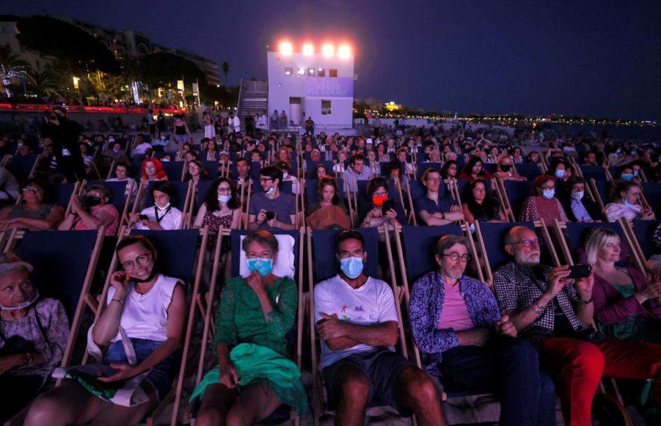 People enjoy a beach front cinema screening at the 74th Cannes on 10 July 2021 (Reuters)