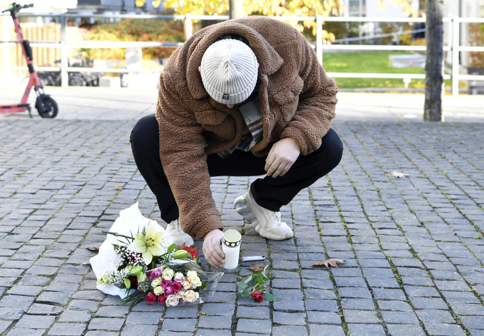 A man places a candle and flower tribute near the site where Swedish rapper Einar was shot to death, in Hammarby Sjostad district in Stockholm, Friday, Oct. 22, 2021. An award-winning 19-year-old Swedish rapper was shot to death in southern Stockholm in an incident that media reports on Friday suggested could be gang-related. The rapper Einar was struck by several bullets in the Hammarby suburb south of central Stockholm and died on the spot late Thursday, police spokesman Ola Osterling told the Swedish news agency TT. (Henrik Montgomery/TT via AP)