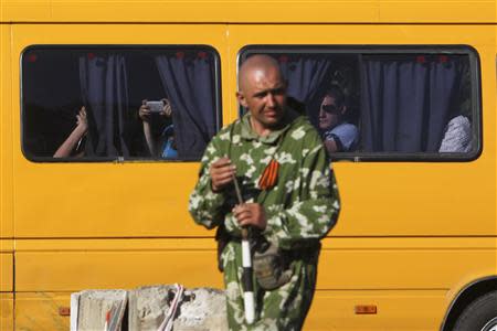 Passengers in a bus look at a pro-Russian activist as he regulates road traffic at a checkpoint outside the eastern Ukrainian city of Luhansk May 21, 2014. REUTERS/Valentyn Ogirenko