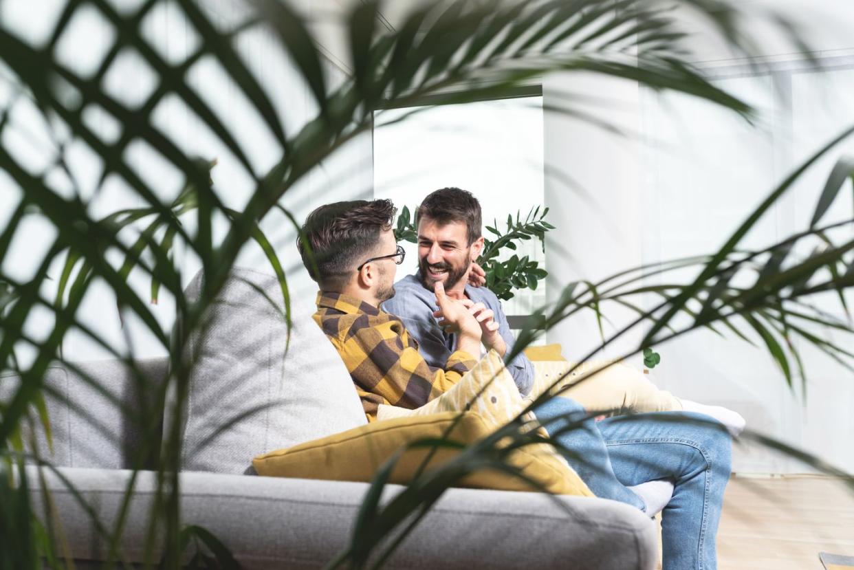 gay couple spending leisure time on sofa at home