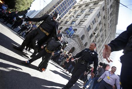 Five-year-old leukemia survivor Miles Scott, dressed as "Batkid" and Batman are escorted by police officers as they return to the Batmobile after they apprehended The Riddler as part of a day arranged by the Make- A - Wish Foundation in San Francisco, California November 15, 2013. REUTERS/Stephen Lam