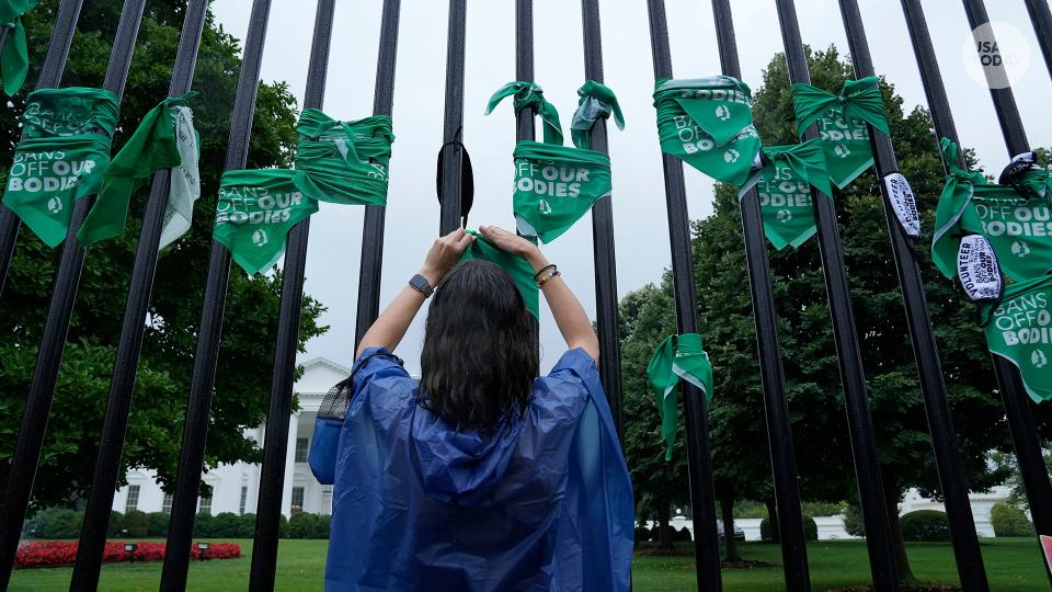 Woman ties bandana to the gates of the White House to protest the overturning of Roe v. Wade.