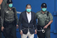 FILE - Jimmy Lai, center, who founded the Apple Daily tabloid, is escorted by Correctional Services officers to get on a prison van before appearing in a court, in Hong Kong on Dec. 12, 2020. (AP Photo/Kin Cheung, File)