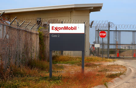 A security guard sits behind a security fence at a gate leading into the ExxonMobil PNG Limited operated Liquefied Natural Gas (LNG) plant at Caution Bay, located on the outskirts of Port Moresby, Papua New Guinea, November 19, 2018. Picture taken November 19, 2018. REUTERS/David Gray