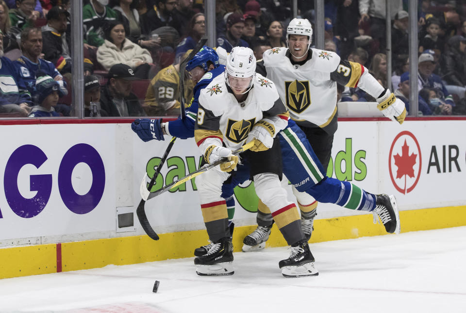 Vancouver Canucks' J.T. Miller, back left, vies for the puck against Vegas Golden Knights' Jack Eichel (9) and Brayden McNabb (3) during the first period of an NHL hockey game in Vancouver, British Columbia, Sunday, April 3, 2022. (Darryl Dyck/The Canadian Press via AP)