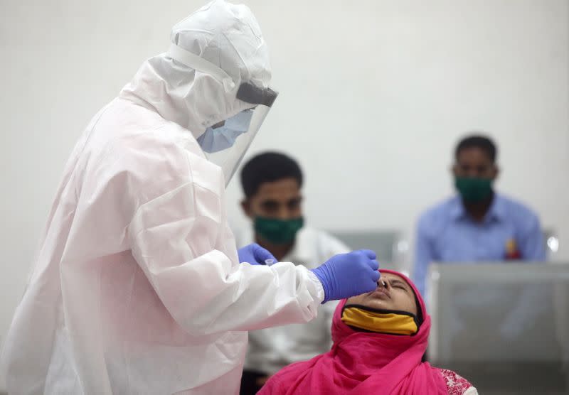 A health worker in a personal protective equipment (PPE) collects a swab sample from a woman, in Mumbai