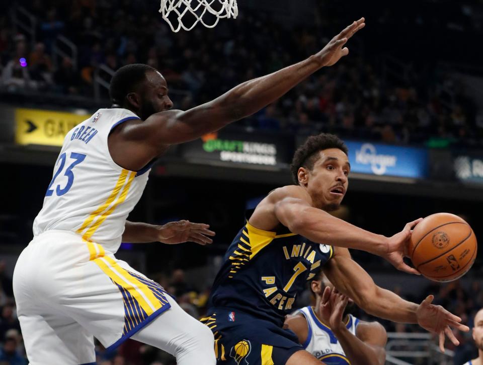 Golden State Warriors forward Draymond Green (23) attempts to block Indiana Pacers guard Malcolm Brogdon (7) as he passes the ball during the first half of a game Monday, Dec. 3, 2021, at Gainbridge Fieldhouse in Indianapolis.