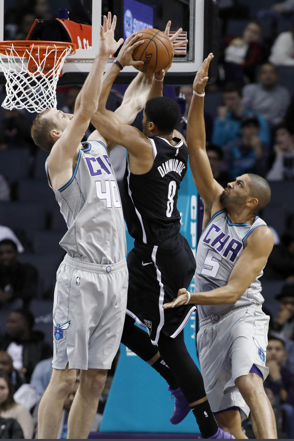 Spencer Dinwiddie (8), de los Nets de Brooklyn, busca el aro entre las marcas de Cody Zeller (40) y Nicolas Batum (5), de los Hornets de Charlotte, en la segunda mitad del partido en Charlotte, Carolina del Norte, el viernes 6 de diciembre de 2019. (AP Foto/Bob Leverone)