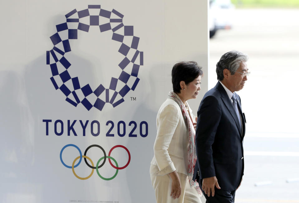 FIEL - In this Aug. 24, 201, file photo, Tokyo Gov. Yuriko Koike, second from right, and Tsunekazu Takeda, president of the Japanese Olympic Committee, walk past the logo of the Tokyo 2020 Olympics during the Olympic flag arrival ceremony at Haneda international airport in Tokyo. The price tag keeps soaring for the 2020 Tokyo Olympics despite local organizers and the International Olympic Committee saying that spending is being cut. (AP Photo/Eugene Hoshiko, File)