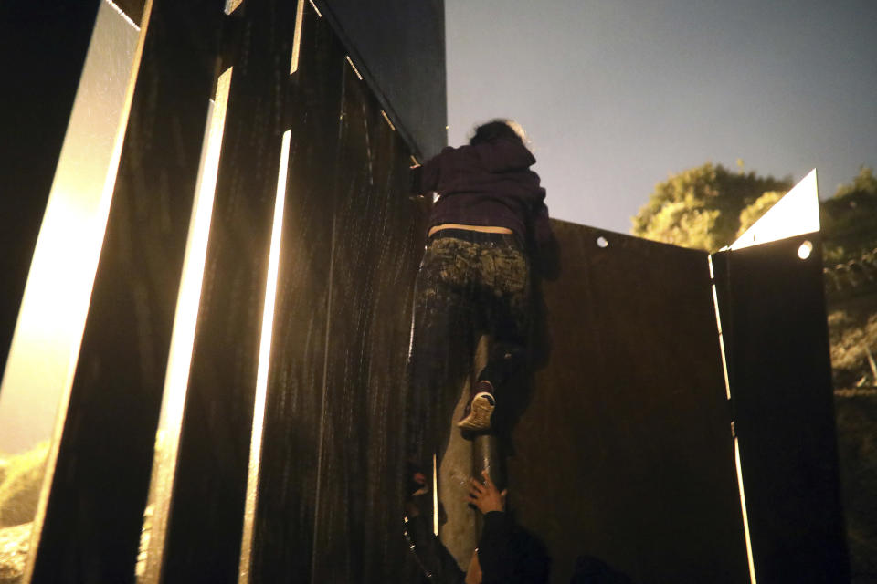 Honduran migrant Jennifer Ramos, 30, successfully climbs over a border barrier, in Tijuana, Mexico, Friday, Nov. 30, 2018. Ramos was detained by U.S. Border Patrol agents as soon after she stepped onto U.S. territory. Thousands of migrants who traveled via a caravan members want to seek asylum in the U.S. but may have to wait months because the U.S. government only processes about 100 of those cases a day at the San Ysidro border crossing in San Diego. (AP Photo/Felix Marquez)