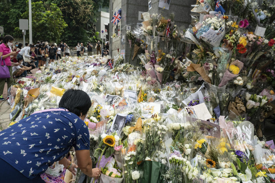 A woman lays flowers as a tribute outside the British Consulate in Hong Kong, Friday, Sept. 16, 2022. In Britain, Thousands of mourners waited for hours Thursday in a line that stretched for almost 5 miles (8 kilometers) across London for the chance to spend a few minutes filing past Queen Elizabeth II's coffin while she lies in state. (AP Photo/Anthony Kwan)