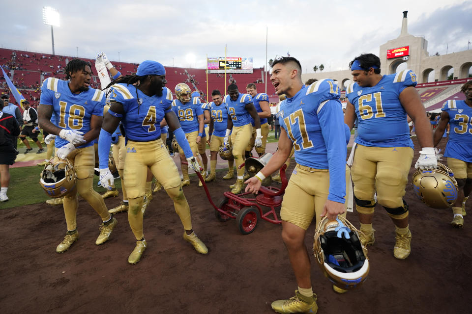 UCLA players take the Southern California bell after a 38-20 win in their NCAA college football game in Los Angeles, Saturday, Nov. 18, 2023. (AP Photo/Ashley Landis)
