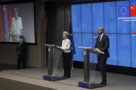 German Chancellor Angela Merkel, at left on a screen, talks during an online press conference with European Commission President Ursula von der Leyen, second right, and European Council President Charles Michel, right, following an EU-China virtual summit at the European Council building in Brussels, Monday, Sept. 14, 2020. Michel, Merkel and Von der Leyen had talks in a videoconference with China's President Xi Jinping. (Yves Herman/Pool Photo via AP)