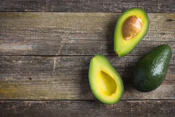 An overhead view of avocados sitting on a wooden table.