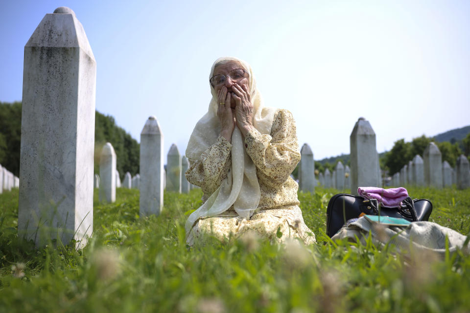 A Bosnian muslim woman mourns next to the grave of her relative, victim of the Srebrenica genocide, in Memorial Centre in Potocari, Bosnia, Tuesday, July 11, 2023. Thousands converge on the eastern Bosnian town of Srebrenica to commemorate the 28th anniversary on Monday of Europe's only acknowledged genocide since World War II. (AP Photo/Armin Durgut)