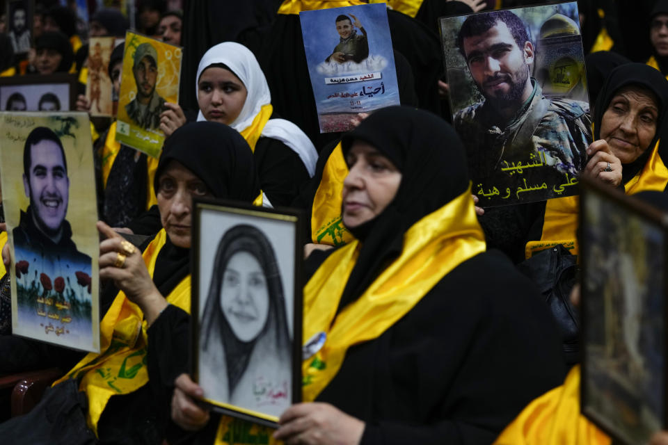 Hezbollah supporters hold pictures of their relatives who died fighting with Hezbollah as they listen to a speech of Hezbollah leader Sayyed Hassan Nasrallah via a video link, during a ceremony marking the "Hezbollah Martyr Day," in the southern Beirut suburb of Dahiyeh, Lebanon, Saturday, Nov. 11, 2023. (AP Photo/Hassan Ammar)