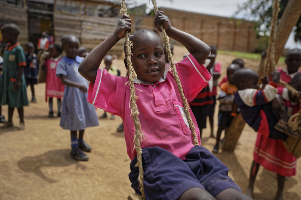 FILE - In this Thursday, June 1, 2017 file photo, Abdu Kabanda, 6, center, who is HIV-positive and receiving HIV treatment from a Ugandan support group because he is able to show a birth certificate to prove his age, plays on a swing during break at the Jovia nursery and primary school in Kyanangazi village, Uganda. In 2019 fewer people in many parts of sub-Saharan Africa are dying of AIDS as treatment becomes more widely available, yet some officials worry that success may be encouraging a sense of complacency. (AP Photo/Ben Curtis, File)