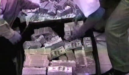 Police gather money in suitcases during a raid at the home belonging to Chinese businessman Zhenli Ye Gon in Mexico City, Mexico is seen in this still image taken from video, in March 2007. Mexican Attorney General/Handout via REUTERS