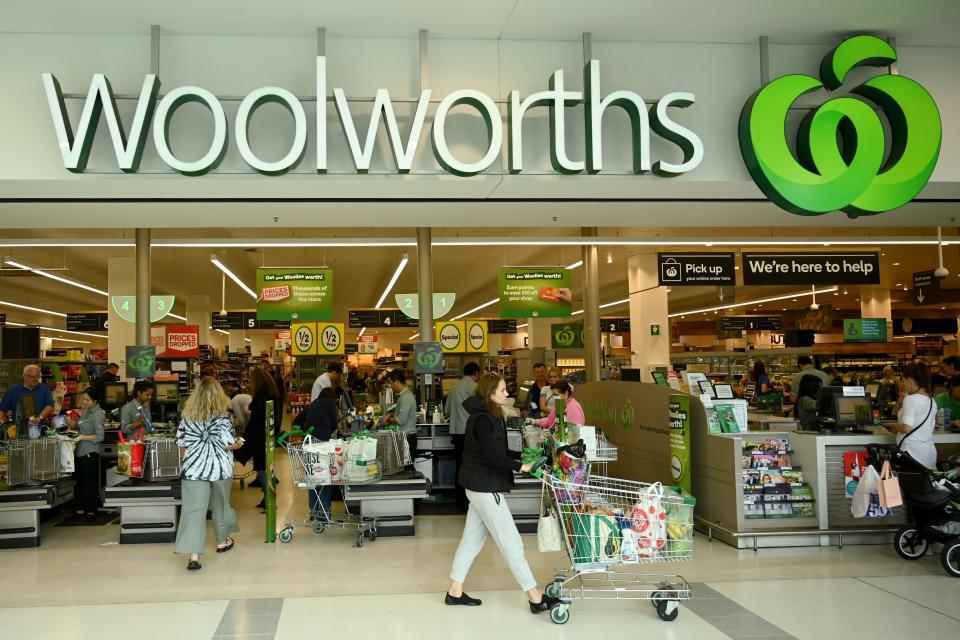 Picture of the outside of a Woolworths store, with people shopping.