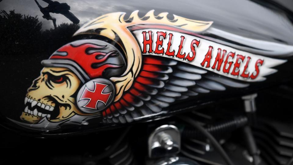 Das Hells Angels-Emblem, ein Totenkopf mit Helm und Flügeln, auf einem Tank eines abgestellten Motorrads.