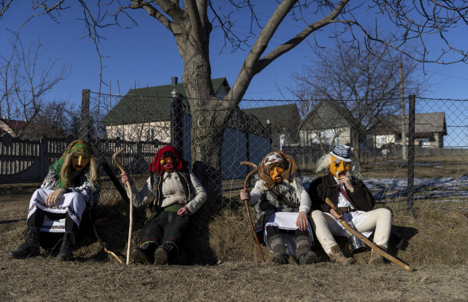 Participants, dressed in traditional costumes, take a break while celebrating the Malanka festival in the village of Krasnoilsk, Ukraine, Friday, Jan. 14, 2022. (AP Photo/Ethan Swope)