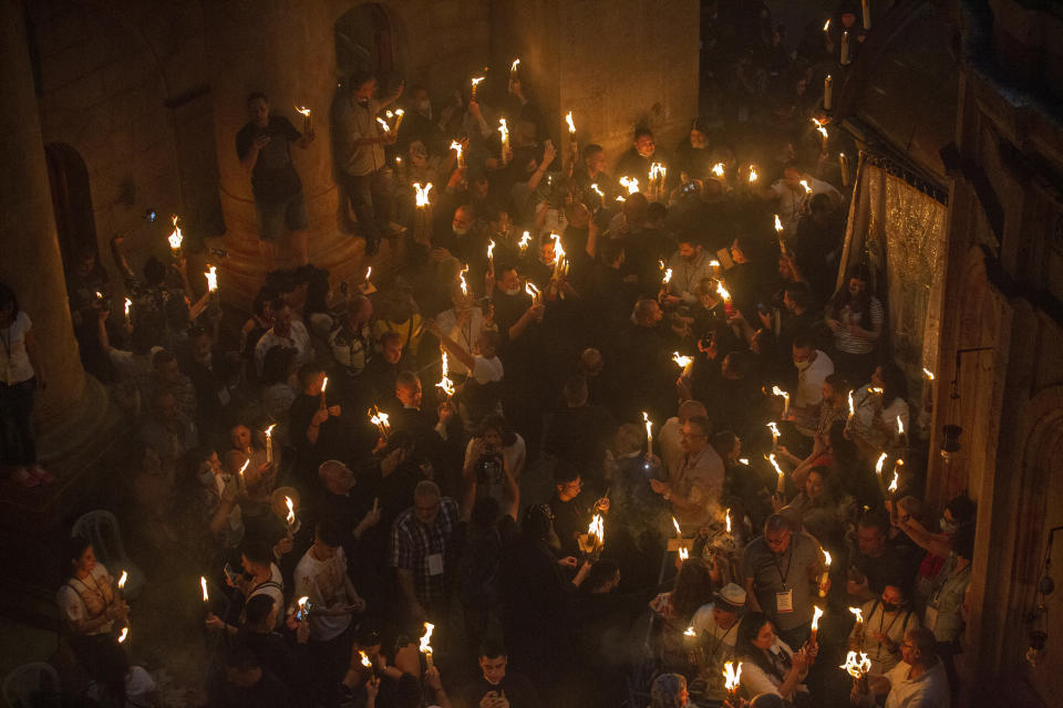 FILE - Christian pilgrims hold candles as they gather during the ceremony of the Holy Fire at Church of the Holy Sepulchre, where many Christians believe Jesus was crucified, buried and rose from the dead, in the Old City of Jerusalem on May 1, 2021. Christians have vowed to defy what they say are new and unfair Israeli restrictions on the "Holy Fire" ceremony to be held Saturday, April 23, 2022 at Christianity's holiest site, raising the possibility of even more religiously-charged unrest in Jerusalem. (AP Photo/Ariel Schalit, File)