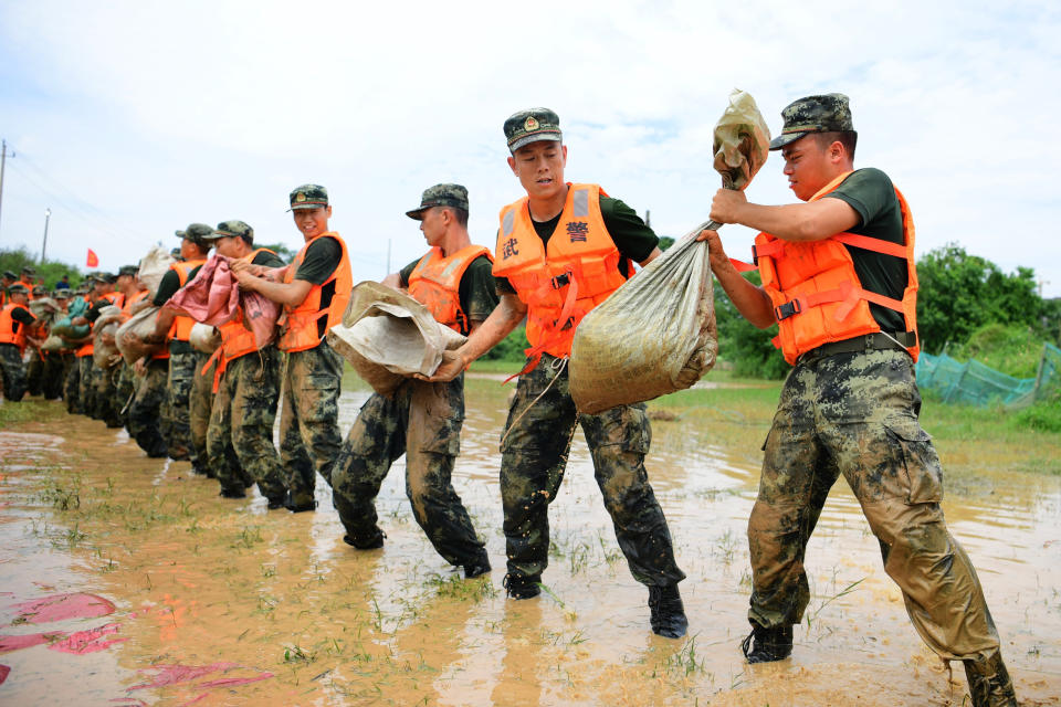 In this photo released by Xinhua News Agency, Chinese paramilitary policemen form a line to move sandbags to reinforce a dyke along the banks of Poyang Lake in Poyang County in eastern China's Jiangxi Province, Sunday, July 12, 2020. Vice Minister of Emergency Management Zheng Guoguang told reporters Monday, July 13, 2020 that the Yangtze River and parts of its watershed have seen the second highest rainfall since 1961 over the past six months. (Cao Xianxun/Xinhua via AP)