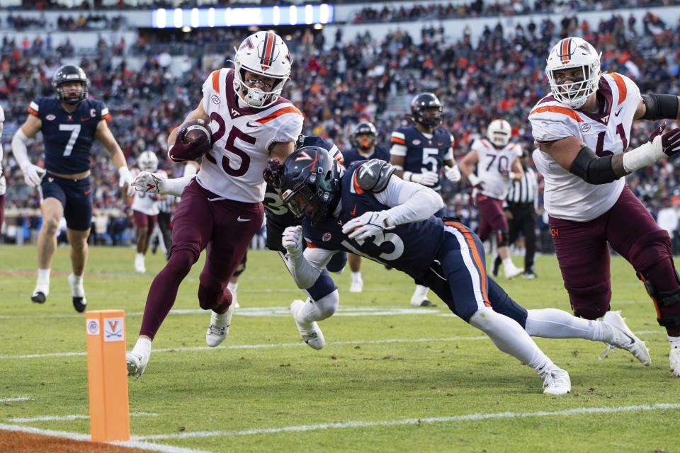 Virginia Tech wide receiver Tucker Holloway (25) runs in for a touchdown against Virginia cornerback Sam Westfall (13) during the first half of an NCAA college football game Saturday, Nov. 25, 2023, in Charlottesville, Va. (AP Photo/Mike Caudill)