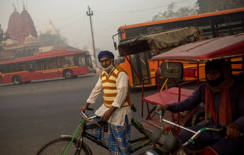 A rickshaw puller waits for customers on a smoggy morning in the old quarters of Delhi