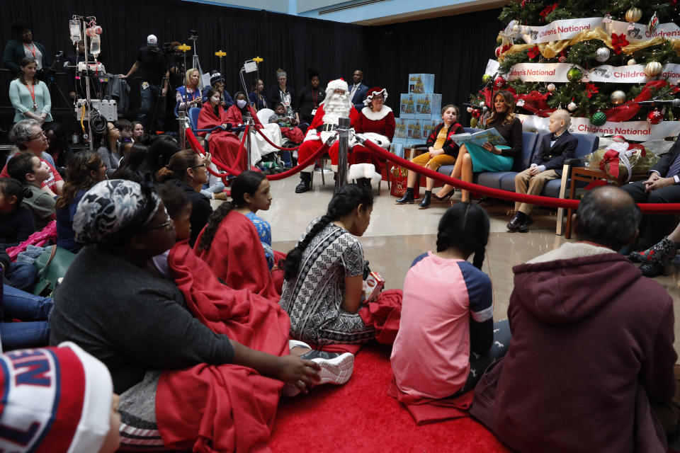 First lady Melania Trump reads a Christmas book to children as she is seated between patients at Children's National Hospital, Sammie Burley, left, and Declan McCahan, right, Friday, Dec. 6, 2019, in Washington. (AP Photo/Jacquelyn Martin)