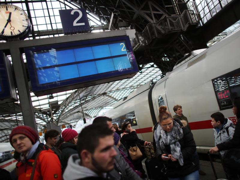 Gestrandet: Bahnreisende stehen unter einer leeren Anzeigetafel auf dem Kölner Hauptbahnhof. Foto: Oliver Berg