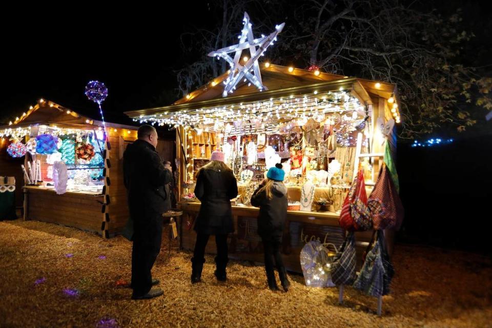 Shoppers gather in front of a cozy, brightly-lit vendor booth at the Cambria Christmas Market on Wednesday, Dec. 14, 2022.