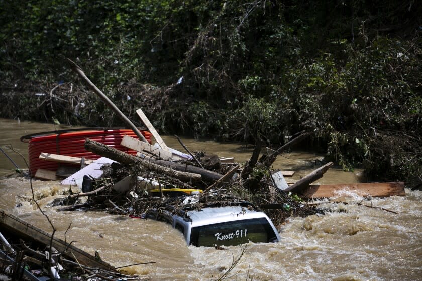 A truck is washed away by floodwaters in the Troublesome Creek near Main Street, in Hindman, Ky., Monday, Aug. 1, 2022. The creek has started to recede, leaving business owners in the town to start cleanup efforts. (Amanda Rossmann/Courier Journal via AP)