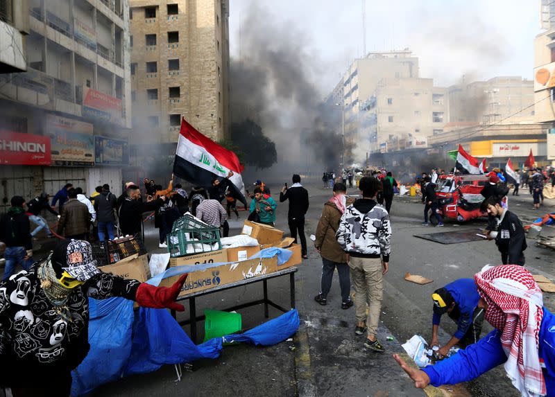 Demonstratos are seen amongst smoke rising from burning tents as Iraqi security forces raid at Tahrir Square during ongoing anti-government protests in Baghdad