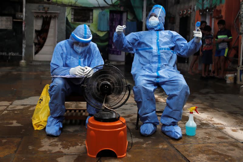 Healthcare workers rest in front of a fan during a check up campaign for the coronavirus disease (COVID-19) at a slum area in Mumbai