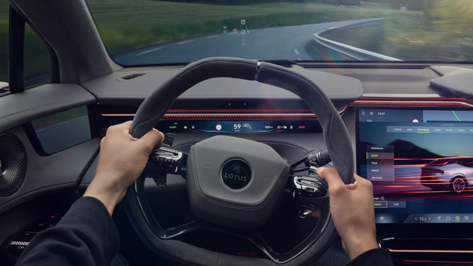 A close-up of a driver's hands on the steering wheel inside a Lotus Eletre S SUV.