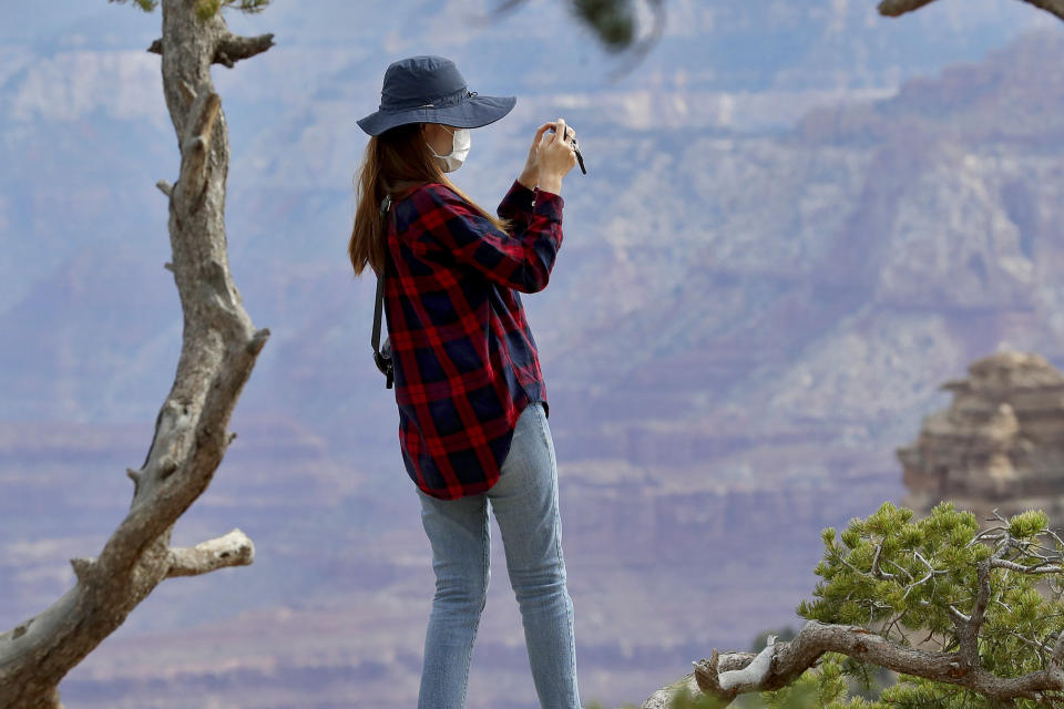 A visitor takes a photo at the Grand Canyon Friday, May 15, 2020, in Grand Canyon, Ariz. Tourists are once again roaming portions of Grand Canyon National Park when it partially reopened Friday morning, despite objections that the action could exacerbate the coronavirus pandemic. (AP Photo/Matt York)