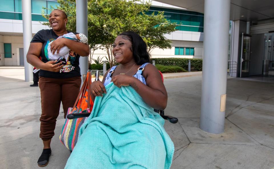 A woman in a wheelchair and another holding a baby.