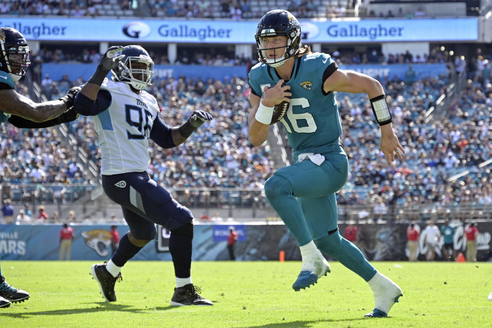 Jacksonville Jaguars quarterback Trevor Lawrence (16) runs for a touchdown past Tennessee Titans defensive end Denico Autry, left, during the second half of an NFL football game, Sunday, Oct. 10, 2021, in Jacksonville, Fla. (AP Photo/Phelan M. Ebenhack)
