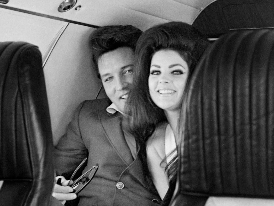 Singer Elvis Presley peeks out from behind his wife, Priscilla Ann Beaulieu, as the couple sit in a chartered jet airplane after their wedding at the Aladdin Hotel in Las Vegas.