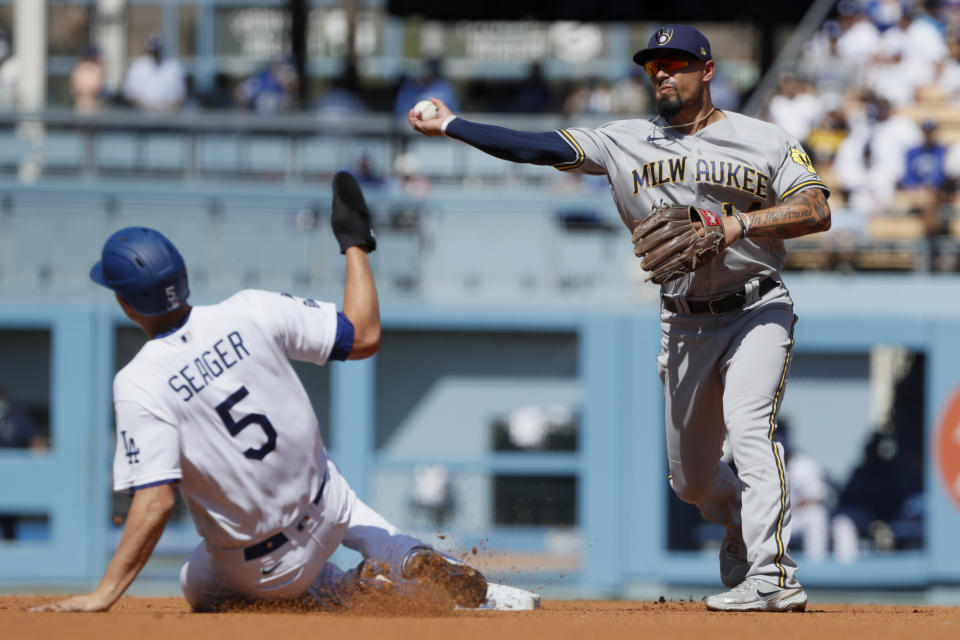 Milwaukee Brewers second baseman Jace Peterson, right, throws over Los Angeles Dodgers' Corey Seager , left, to get Trea Turner at first for a double play during the first inning of a baseball game in Los Angeles, Sunday, Oct. 3, 2021. (AP Photo/Alex Gallardo)