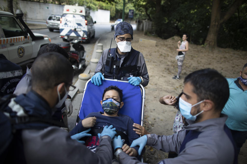 Wearing masks to curb the spread of the new coronavirus, Angels of the Road volunteer paramedics take a boy on a stretcher to their ambulance after he was involved in a motorcycle accident in Caracas, Venezuela, Thursday, Feb. 4, 2021. Despite receiving no paychecks, its roughly 40 paramedics are ready at a moment’s notice to jump onto motorcycles and fire up their single ambulance and race into the streets. (AP Photo/Ariana Cubillos)