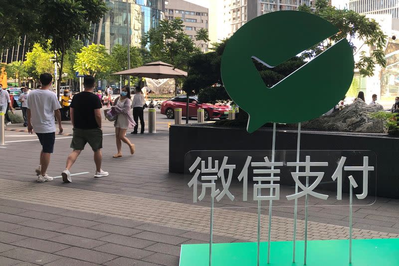 People walk past a Wechat Pay sign at the Tencent company headquarters in Shenzhen