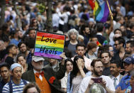 <p>A man walks through the crowd holding a sign during a vigil and memorial for victims of the Orlando nightclub shootings near the historic Stonewall Inn, a gay bar, on Monday, June 13, 2016, in New York. (Photo: Kathy Willens/AP) </p>