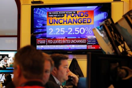Traders work below a screen showing the Fed rate will remain unchanged on the floor of the New York Stock Exchange in New York